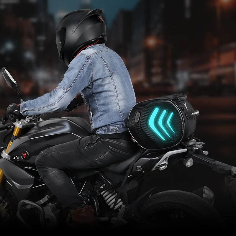 Person riding a motorcycle with a glowing saddlebag at night.