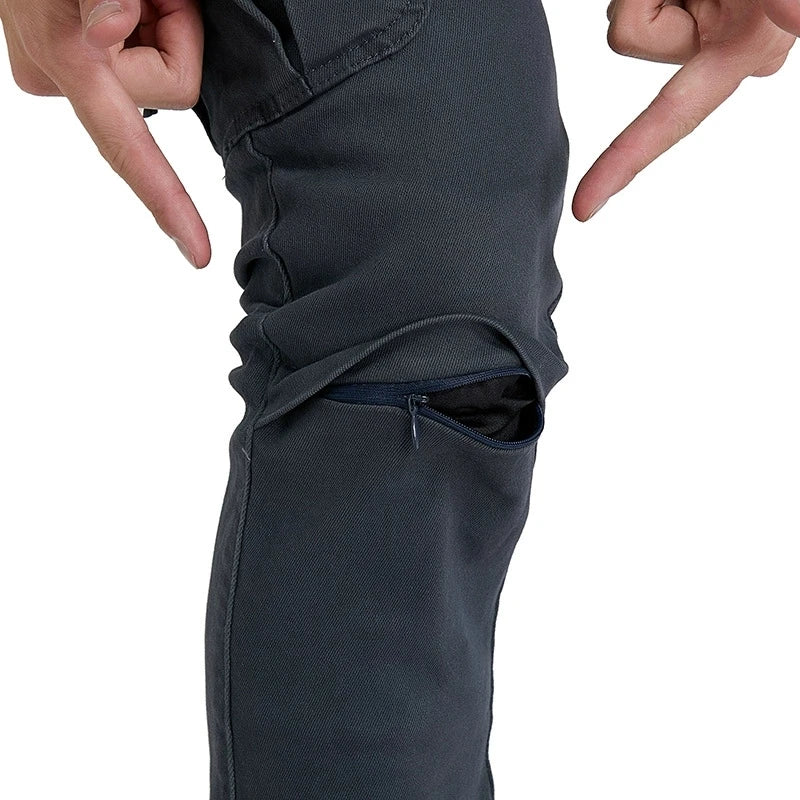 Person pointing to a pocket on dark pants against a white background
